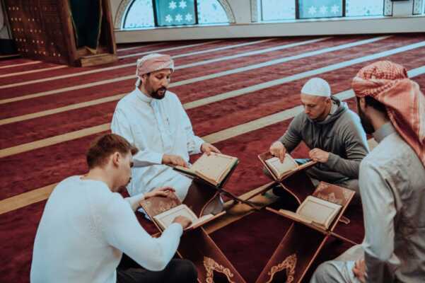 A group of Muslims reading the holy book of the Quran in a modern mosque during the Muslim holiday of Ramadan.