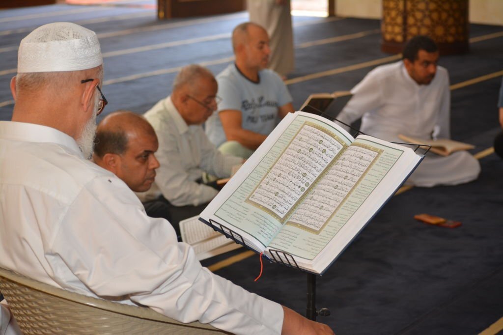 Cairo, Egypt, July 8 2022: A Noble Quran reading ring inside a mosque at the day of Arafah or Arafat before Eid Al-Adha, a group of people reading and learning Quran with an Islamic Imam or preacher