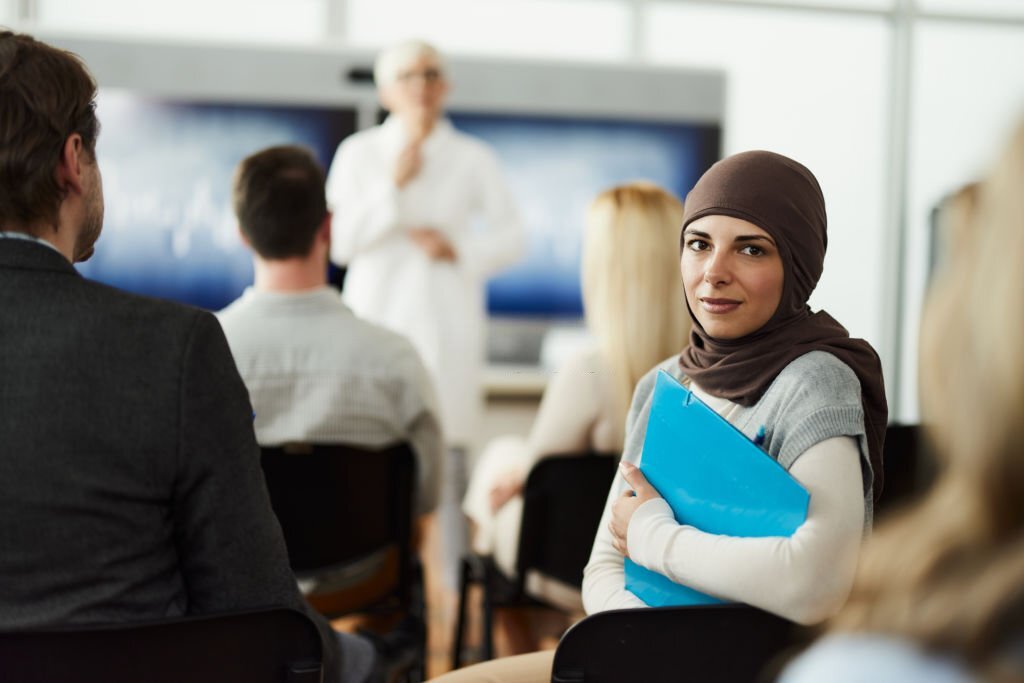 Young Arab woman attending a medical seminar in board room and looking at camera.
