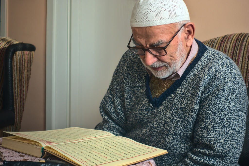 Elderly Turkish muslim male reciting the holy book of Islam, Qur'an in Ramadan month before iftar