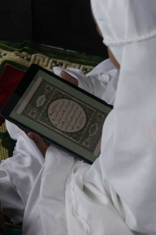Muslim girl reading electronic Quran on tablet
