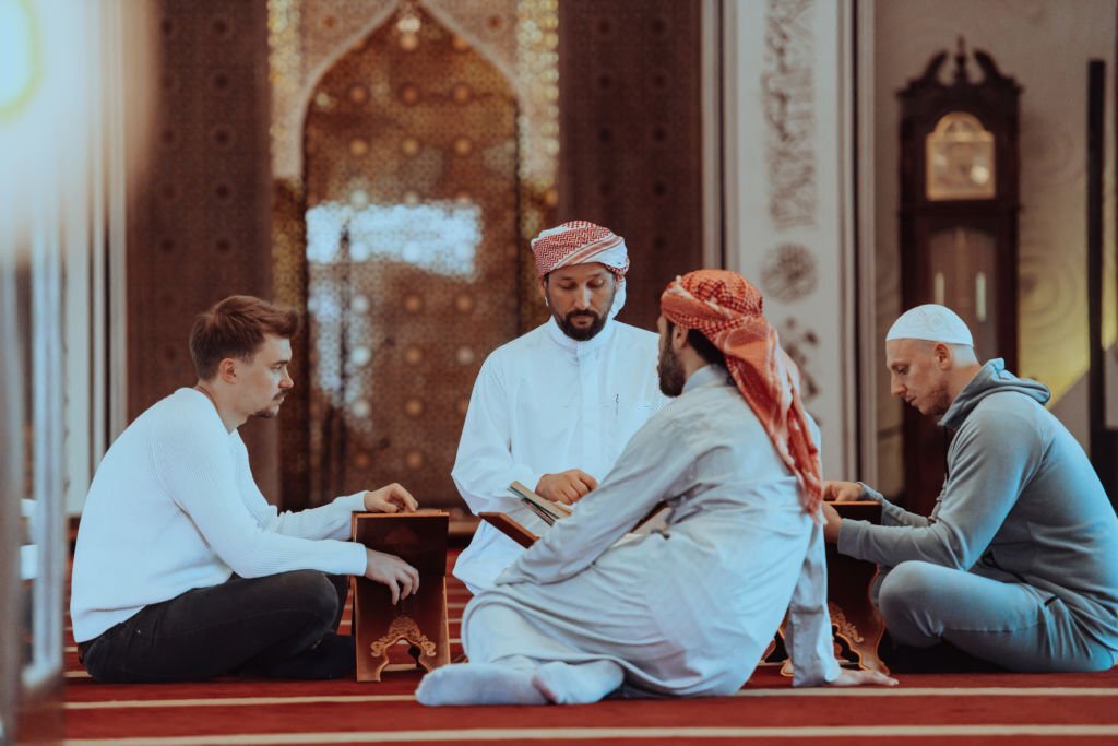 A group of Muslims reading the holy book of the Quran in a modern mosque during the Muslim holiday of Ramadan.
