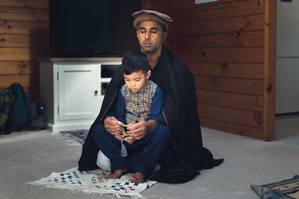Man performing Dhikr while kid sitting on fathers lap.